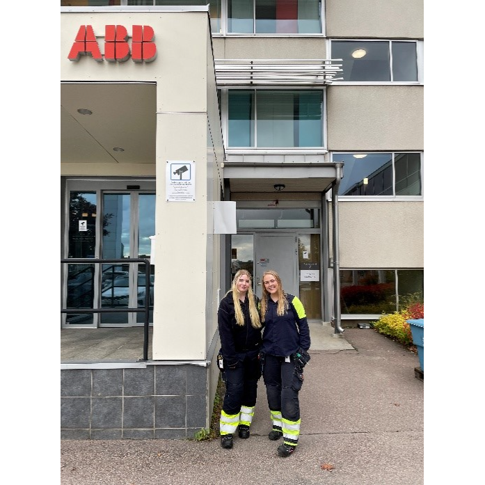 Två kvinnor står framför en byggnad där det står ABB på en pelare. Den ena kvinnan är handledare åt den andra genom Tekniksprånget. 