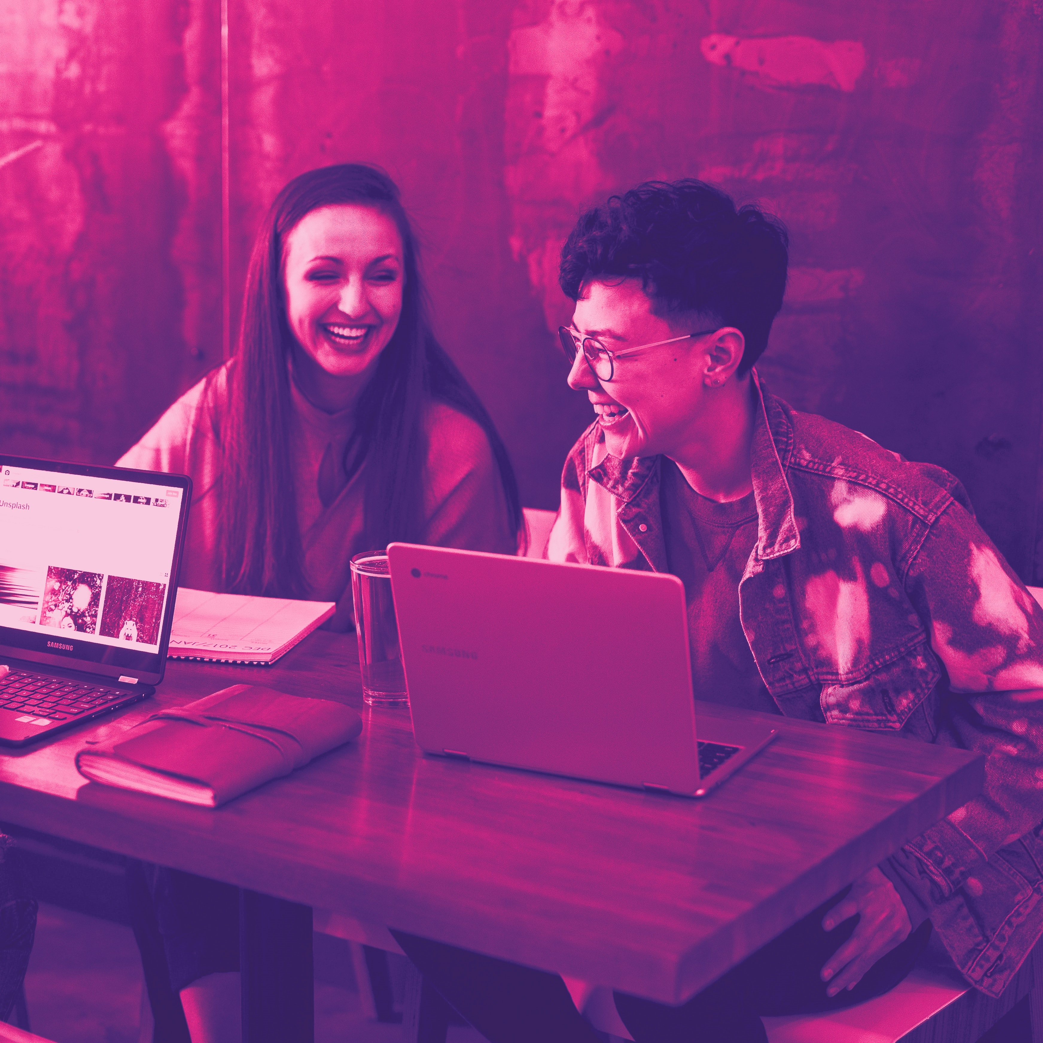 Three people laugh while working on their computers.