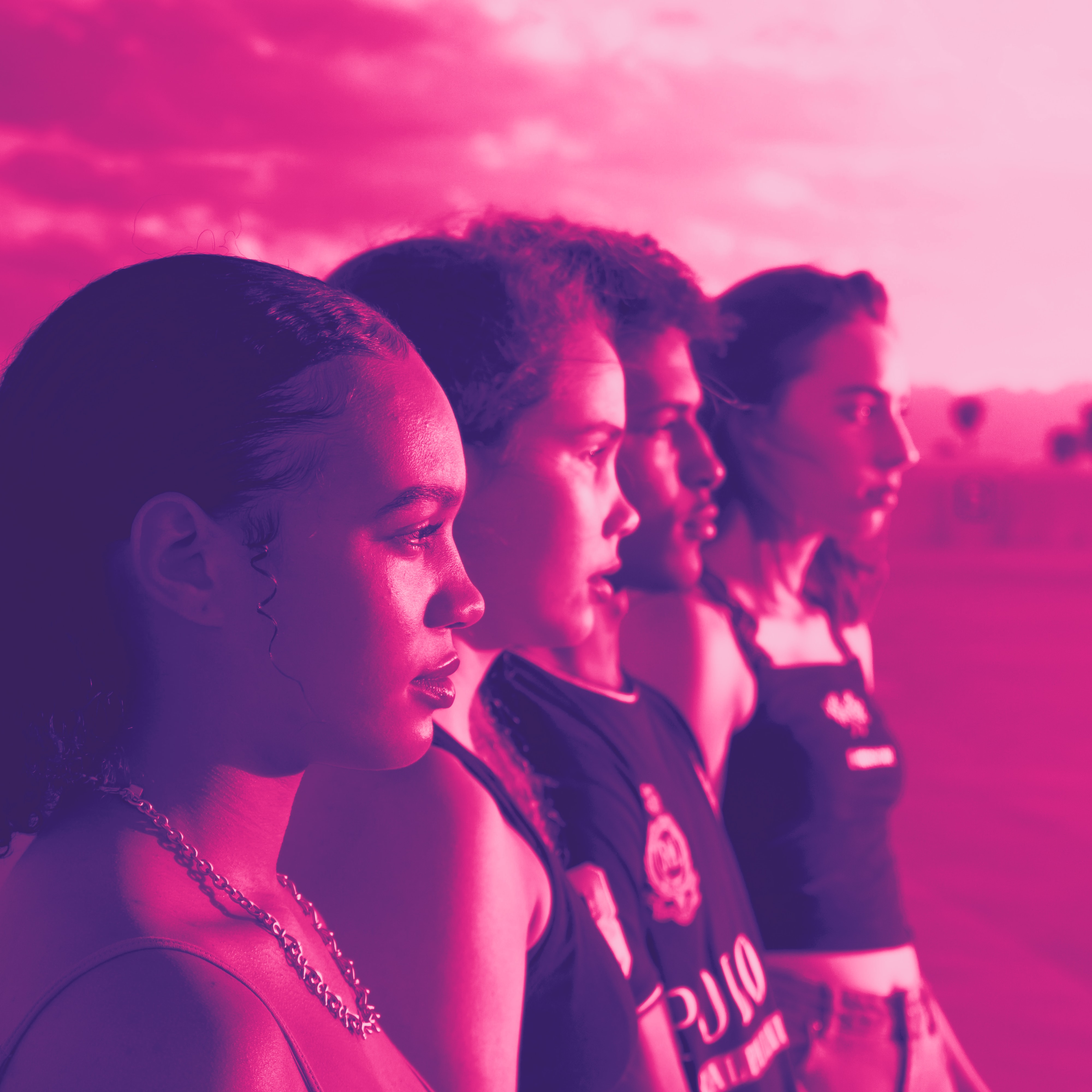 Four young people stand in a row in profile, their eyes fixed on their right. With pink filter