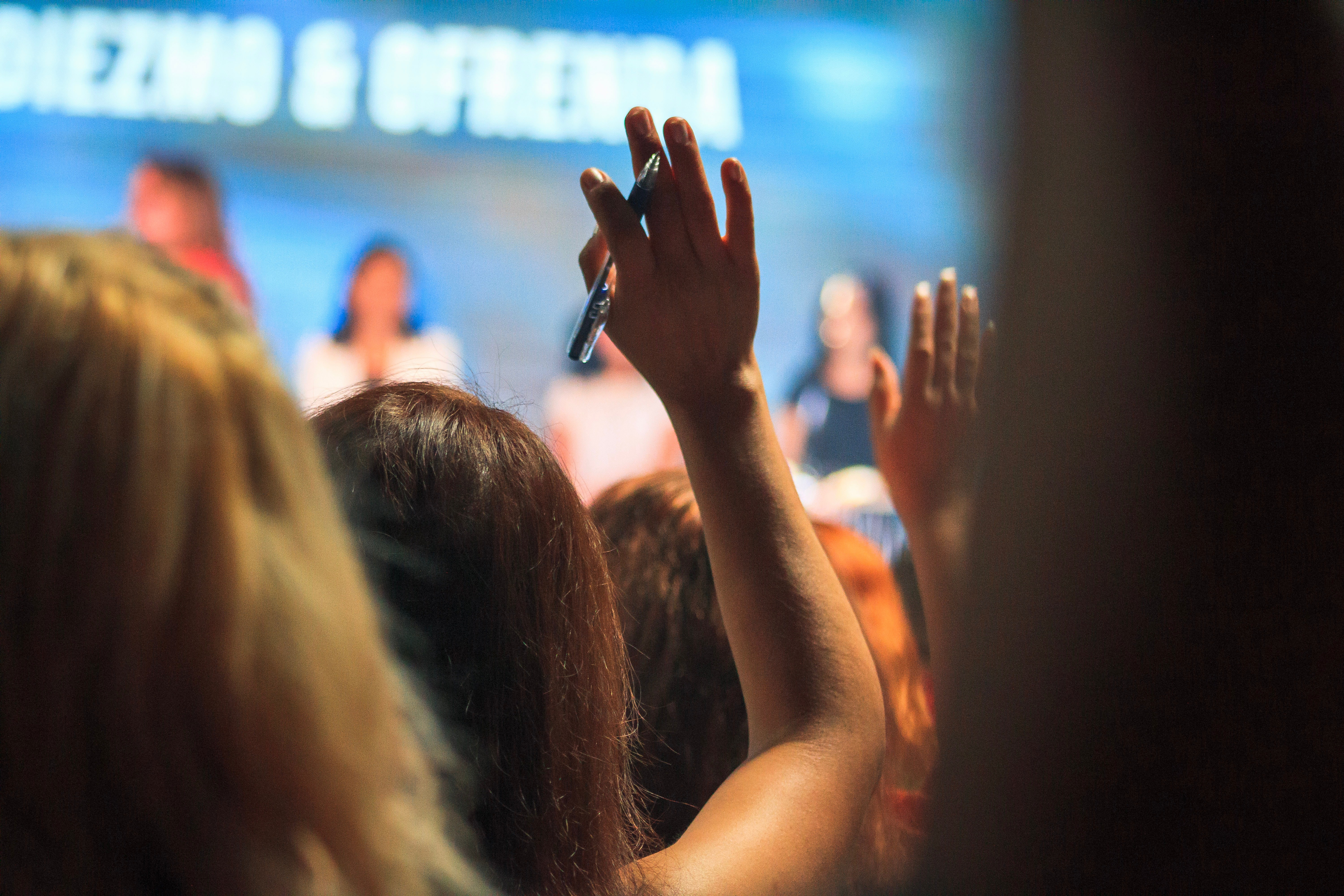 A person raises their hand at a seminar. 