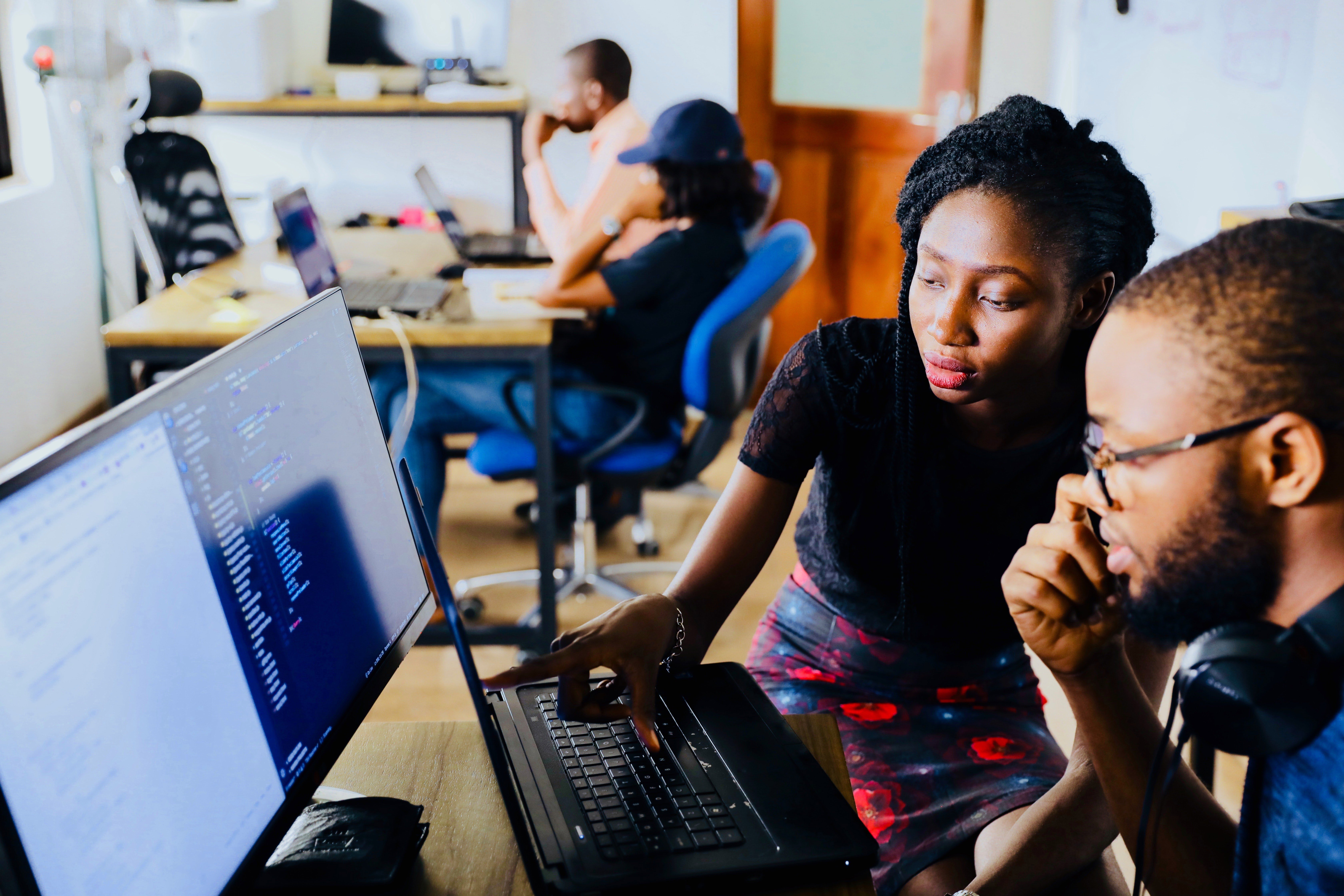 Two people sitting at a computer screen and thinking