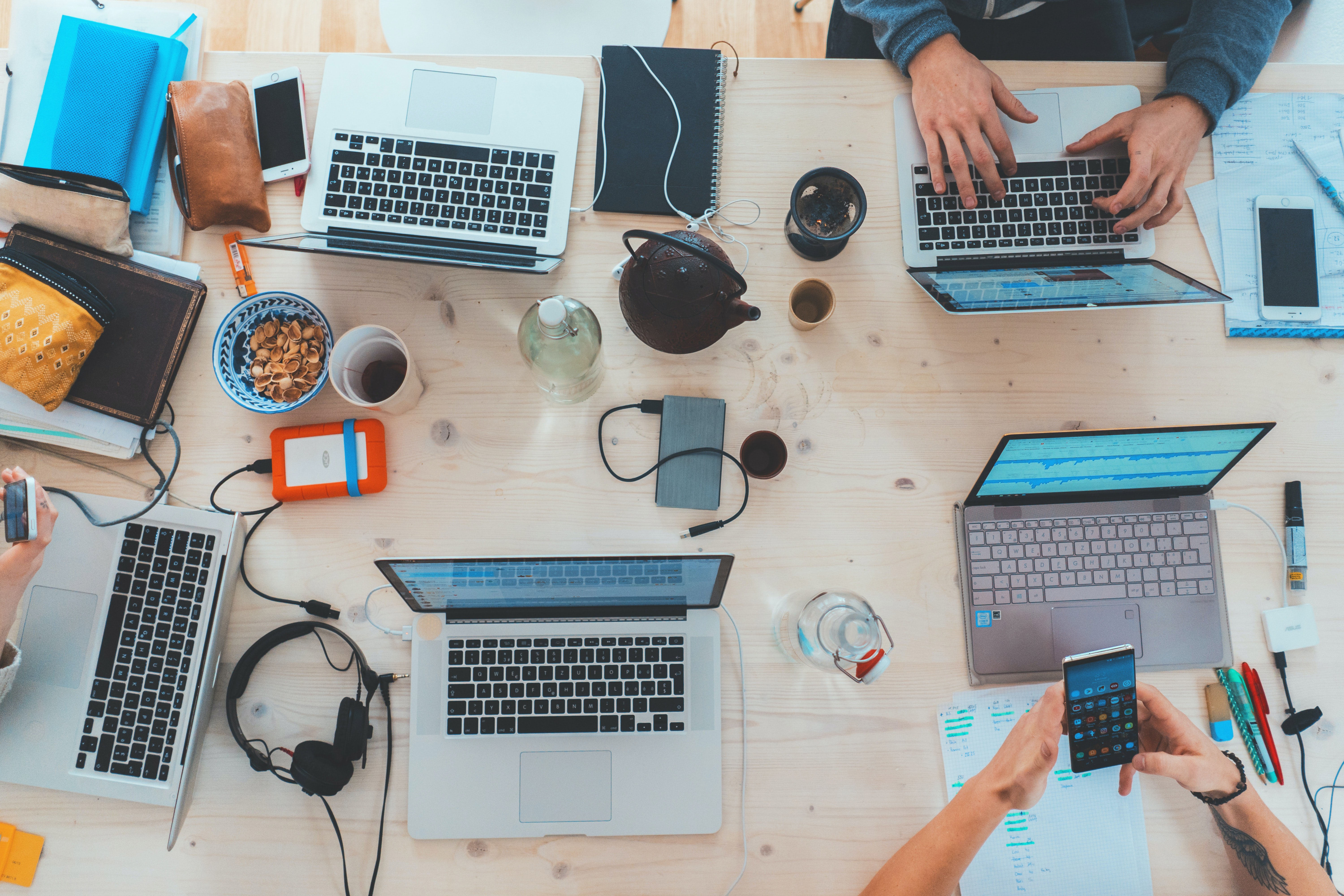 A desk filled with computers, cables, and people working. Gives a wonderfully messy feeling