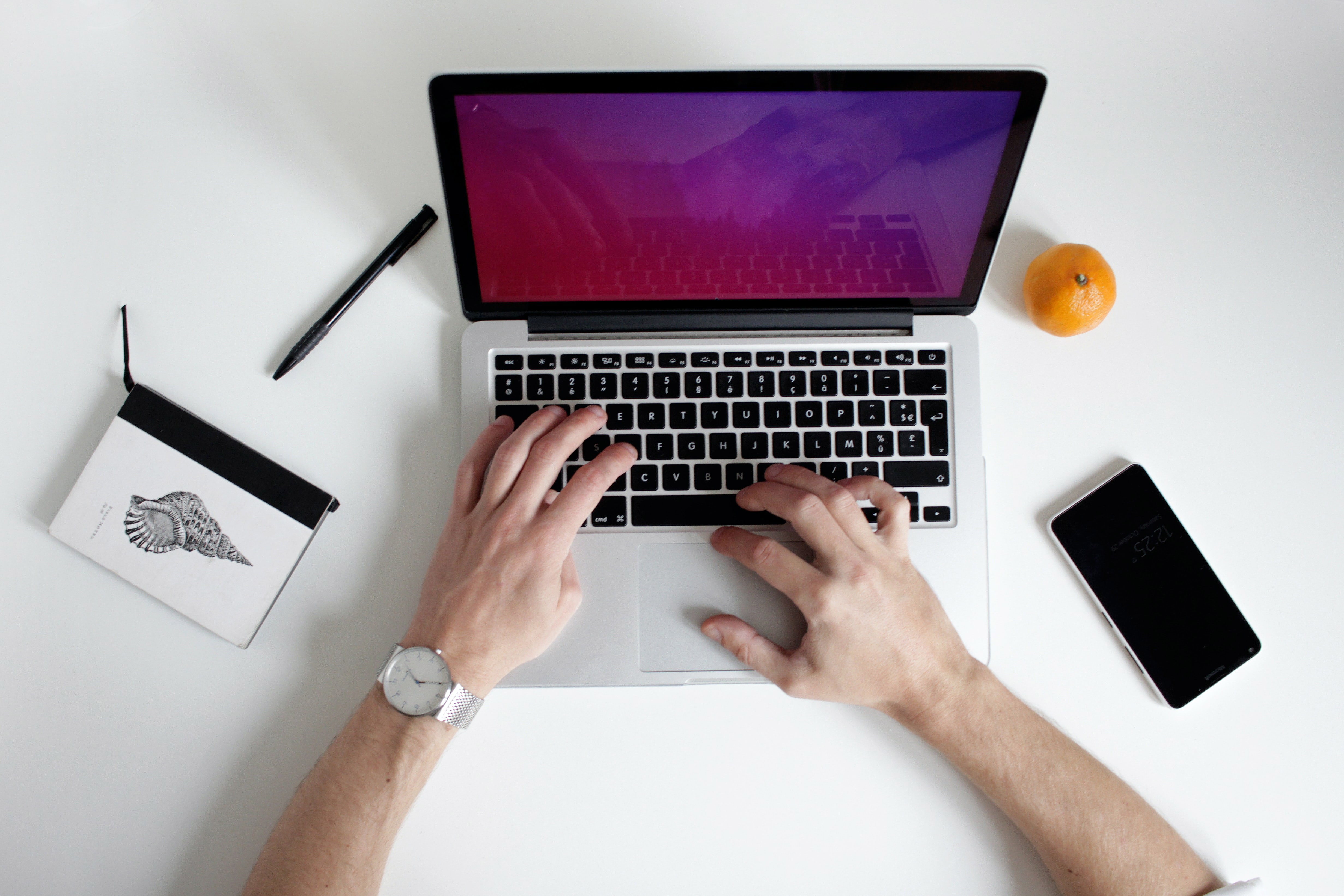 A laptop is visible from above with hands typing on the keyboard.